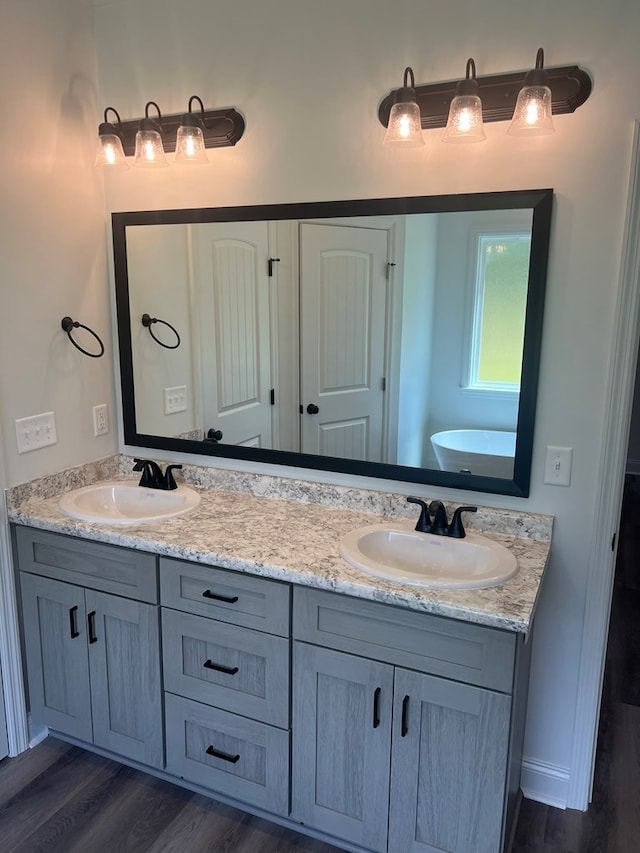 bathroom featuring double vanity, wood finished floors, and a sink