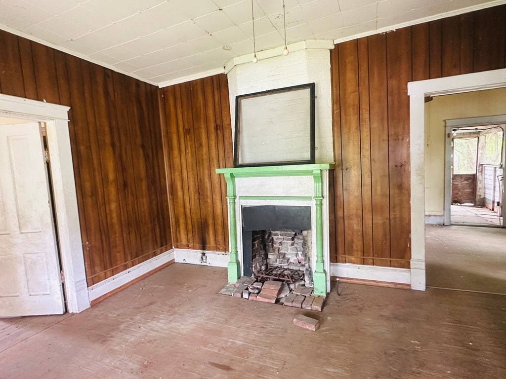 unfurnished living room with a fireplace and wooden walls