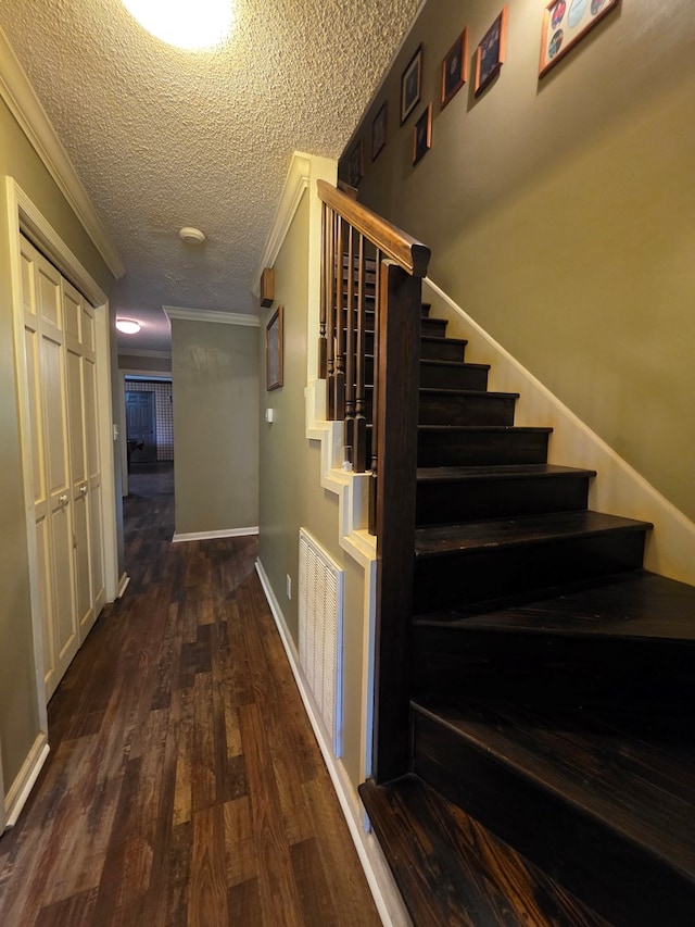 stairs with wood finished floors, ornamental molding, a textured ceiling, and baseboards