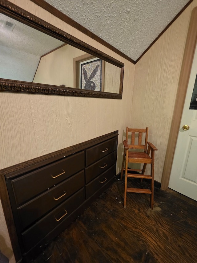 sitting room featuring a textured ceiling, dark wood-type flooring, and vaulted ceiling