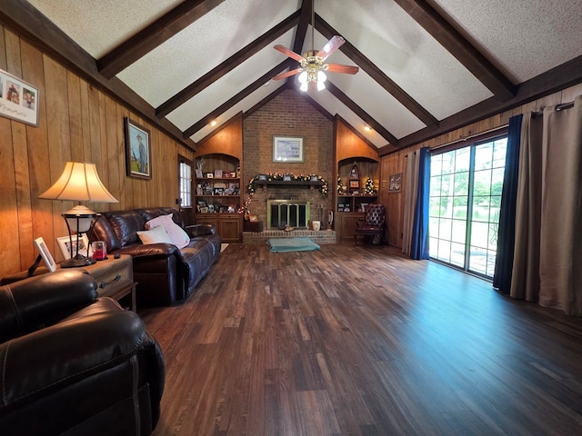 living room with wood finished floors, wooden walls, ceiling fan, a fireplace, and a textured ceiling