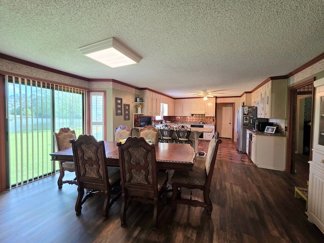 dining area featuring dark wood-type flooring, a textured ceiling, ornamental molding, and ceiling fan