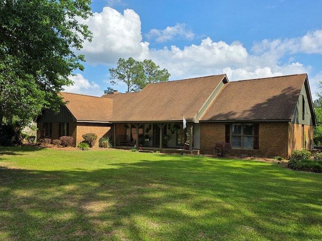 view of front of home with a front lawn, brick siding, and roof with shingles