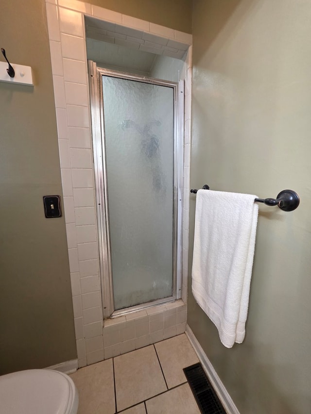 bathroom with a shower stall, tile patterned flooring, and toilet