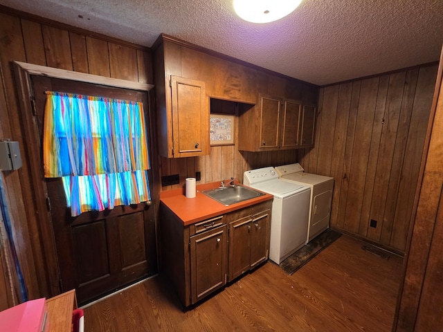clothes washing area with cabinet space, dark wood-style floors, washer and dryer, a textured ceiling, and wooden walls
