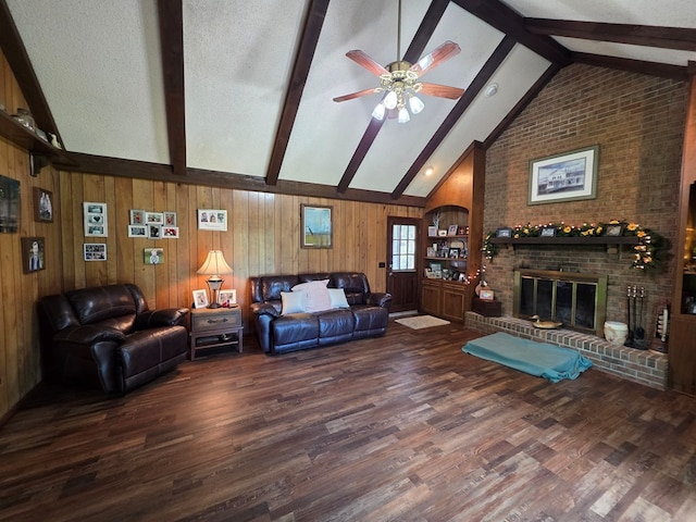 living area with beam ceiling, wood finished floors, ceiling fan, a fireplace, and wooden walls