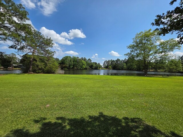 view of green lawn featuring a water view