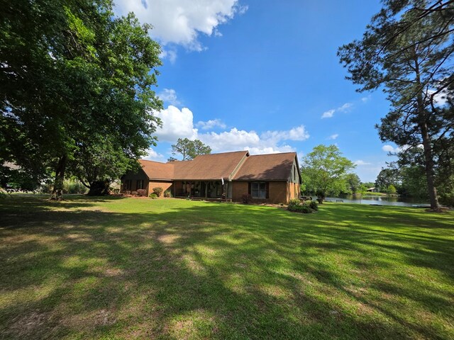 rear view of property featuring a water view and a lawn