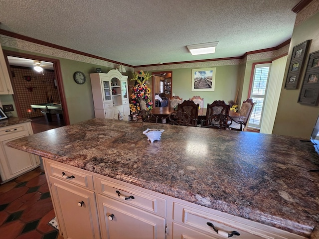 kitchen featuring a textured ceiling, dark countertops, crown molding, and white cabinets