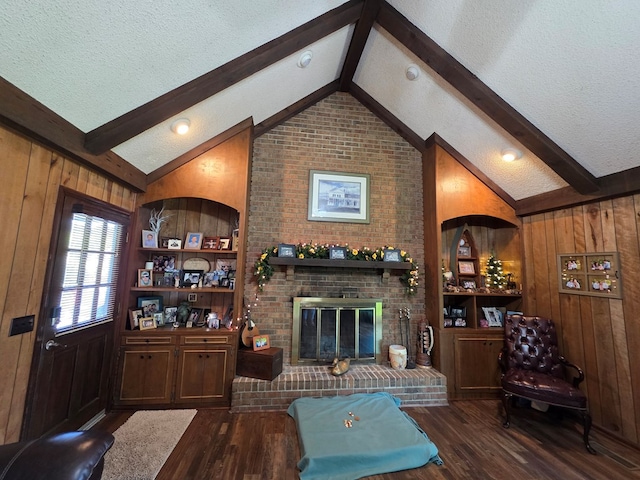 living room with wood finished floors, wood walls, a textured ceiling, and a brick fireplace