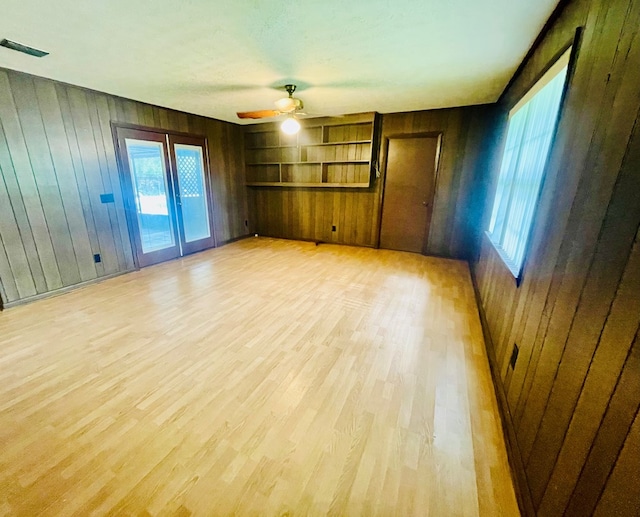 111 Van Deman Ct, Fitzgerald, GA 31750 - unfurnished room featuring light wood-style floors, wood walls, ceiling fan, healthy amount of natural light, and built in shelves
