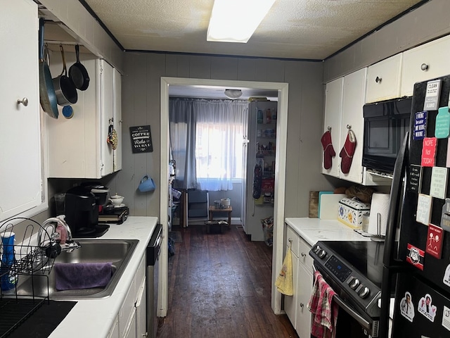 kitchen featuring dark wood-type flooring, white cabinetry, black appliances, light countertops, and a sink