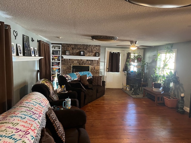 living room with a textured ceiling, wood finished floors, ceiling fan, and a fireplace