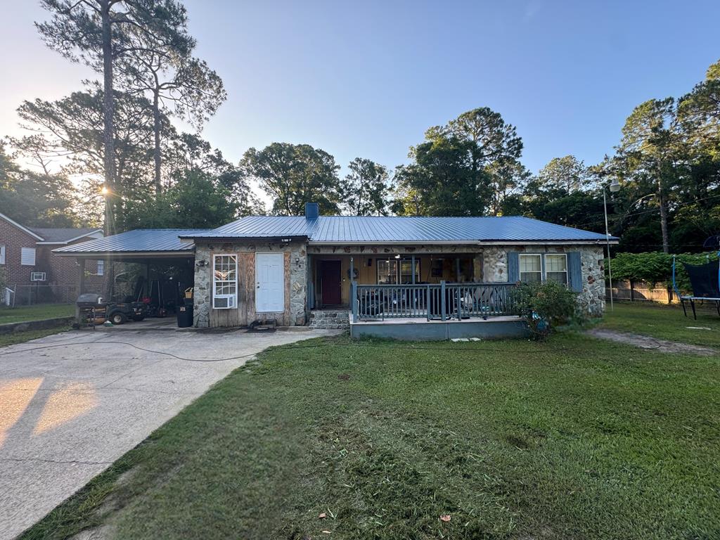 1003 Davis Ave, Tifton, GA 31794 - ranch-style house featuring stone siding, a porch, a trampoline, and a chimney