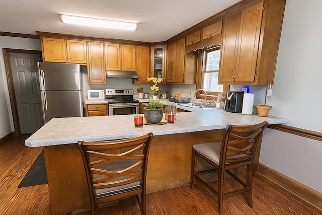 2211 Greenoch Ave, Albany, GA 31721 - kitchen featuring stainless steel appliances, under cabinet range hood, a peninsula, dark wood-style flooring, and a breakfast bar