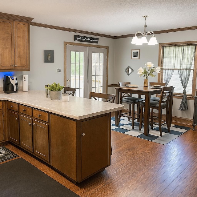 2211 Greenoch Ave, Albany, GA 31721 - kitchen featuring a chandelier, a peninsula, dark wood-style flooring, light countertops, and crown molding