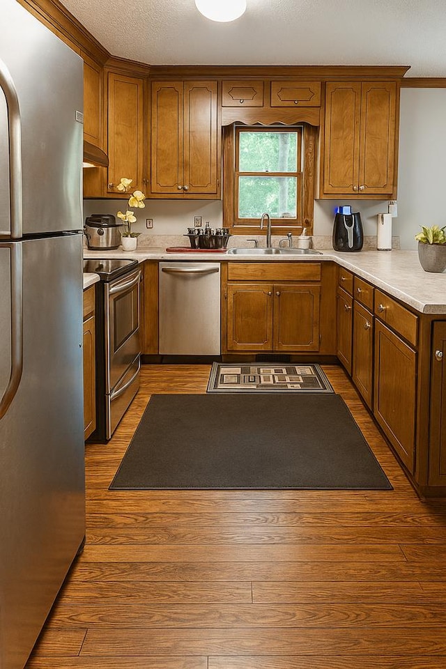 2211 Greenoch Ave, Albany, GA 31721 - kitchen with stainless steel appliances, range hood, wood finished floors, brown cabinetry, and crown molding