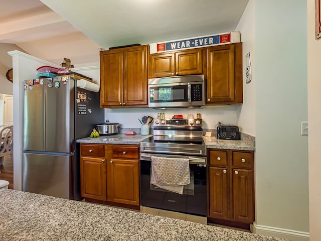 127 Carol Cir, Fitzgerald, GA 31750 - kitchen featuring stainless steel appliances, brown cabinetry, and light stone counters