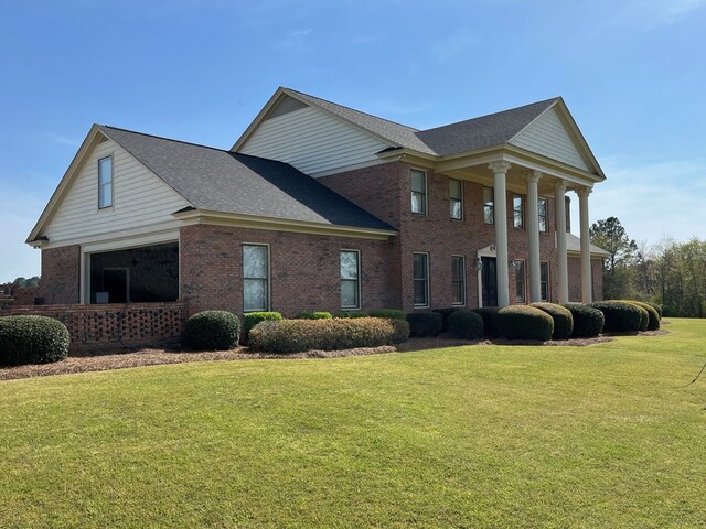 view of front of house featuring a front yard, a shingled roof, and brick siding
