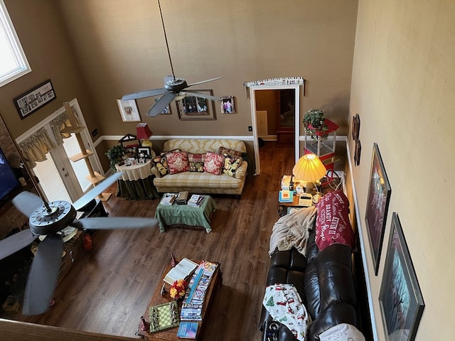 living area featuring a towering ceiling, a ceiling fan, and wood finished floors