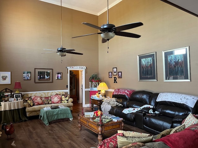 living room with crown molding, ceiling fan, a towering ceiling, and wood finished floors