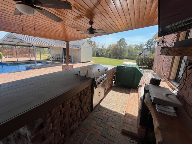 view of patio / terrace featuring a grill, a ceiling fan, glass enclosure, an outdoor pool, and an outdoor kitchen