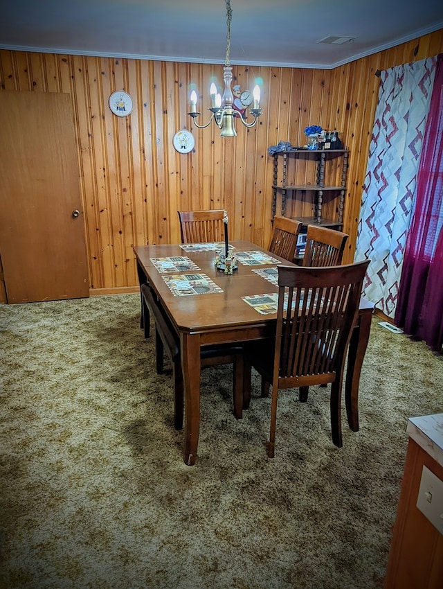 dining room with visible vents, an inviting chandelier, crown molding, carpet floors, and wooden walls