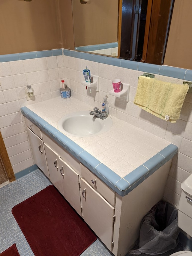 bathroom featuring vanity, a wainscoted wall, tile patterned flooring, and tile walls