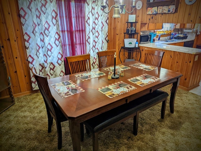 dining room with wooden walls, a notable chandelier, baseboards, and carpet floors
