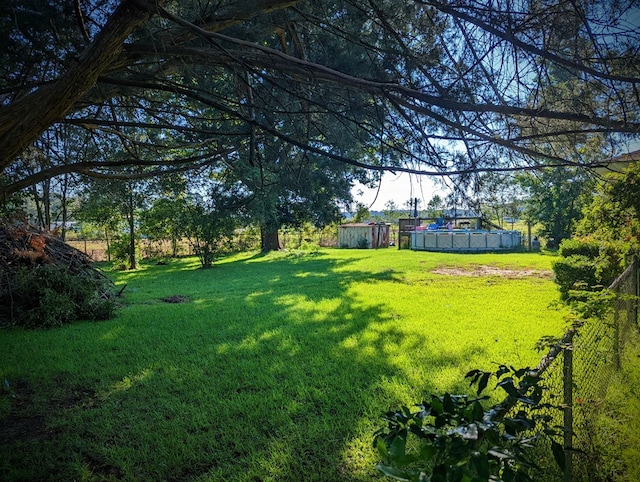 view of yard featuring a shed, a pool, and an outdoor structure