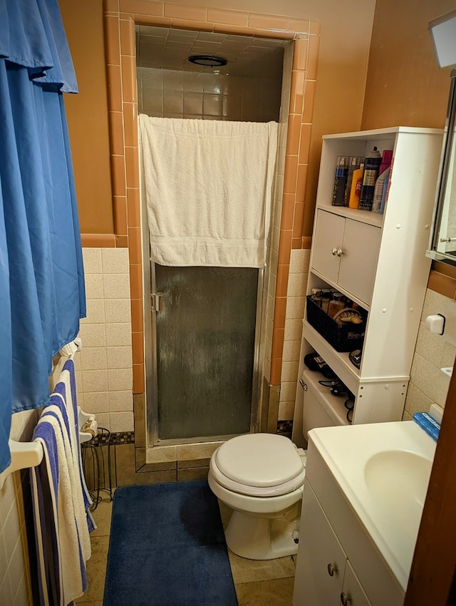 full bathroom featuring vanity, toilet, tile walls, a stall shower, and tile patterned floors