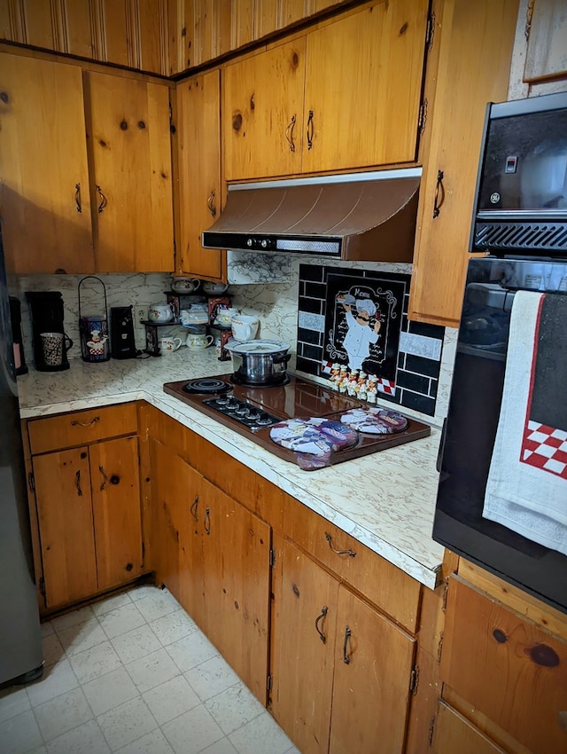 kitchen with backsplash, light countertops, black appliances, and under cabinet range hood