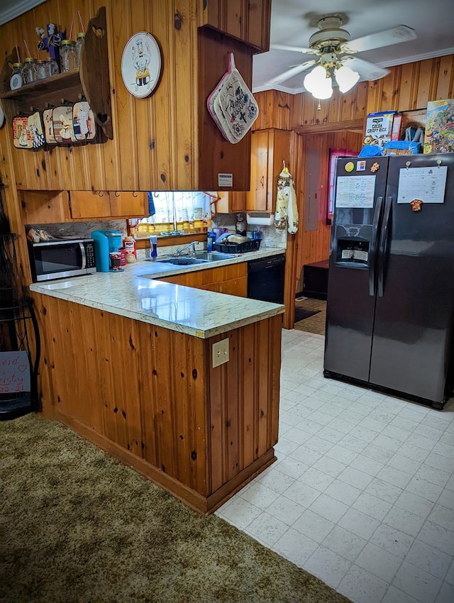 kitchen with a peninsula, a ceiling fan, black appliances, brown cabinets, and a sink