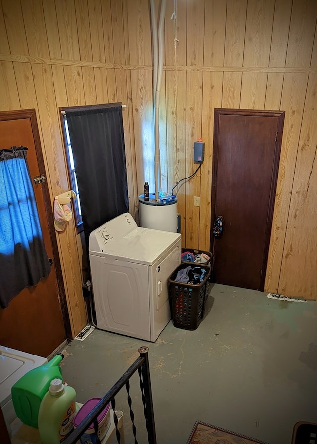 clothes washing area with water heater, washer / clothes dryer, laundry area, and wood walls