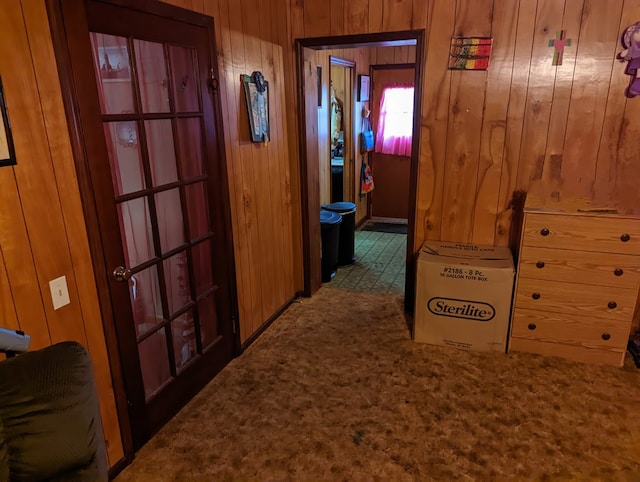 corridor featuring wooden walls and carpet flooring