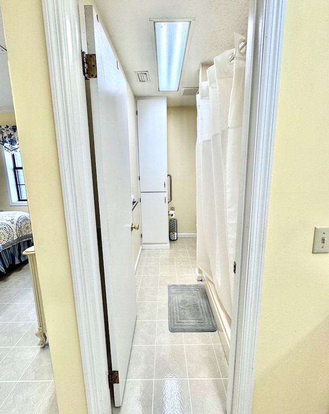 ensuite bathroom with tile patterned floors, visible vents, a shower with curtain, and connected bathroom