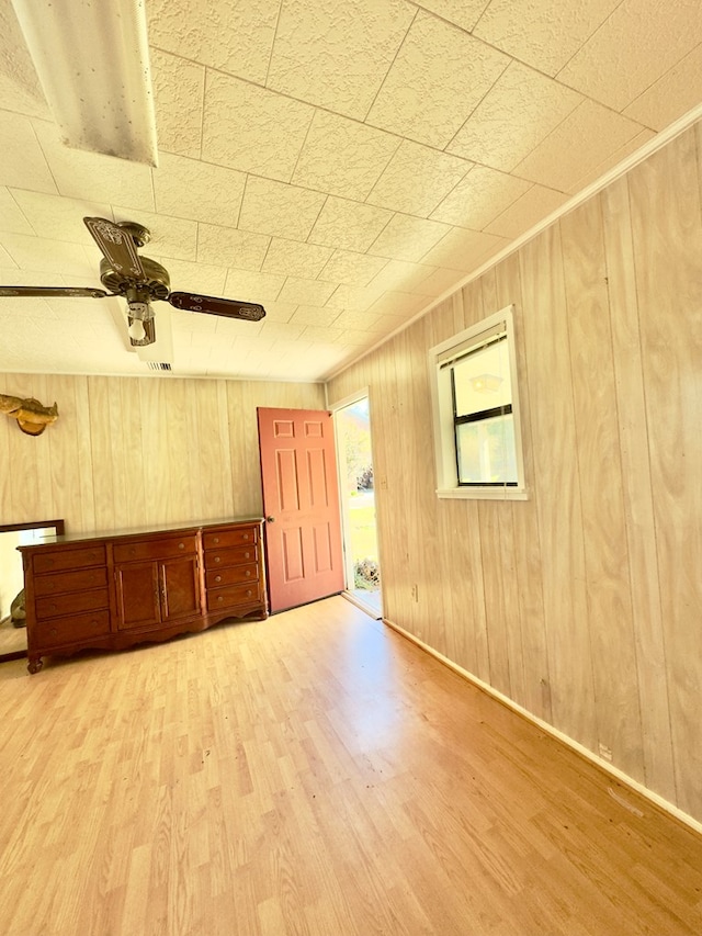 empty room with wooden walls, ceiling fan, and wood finished floors