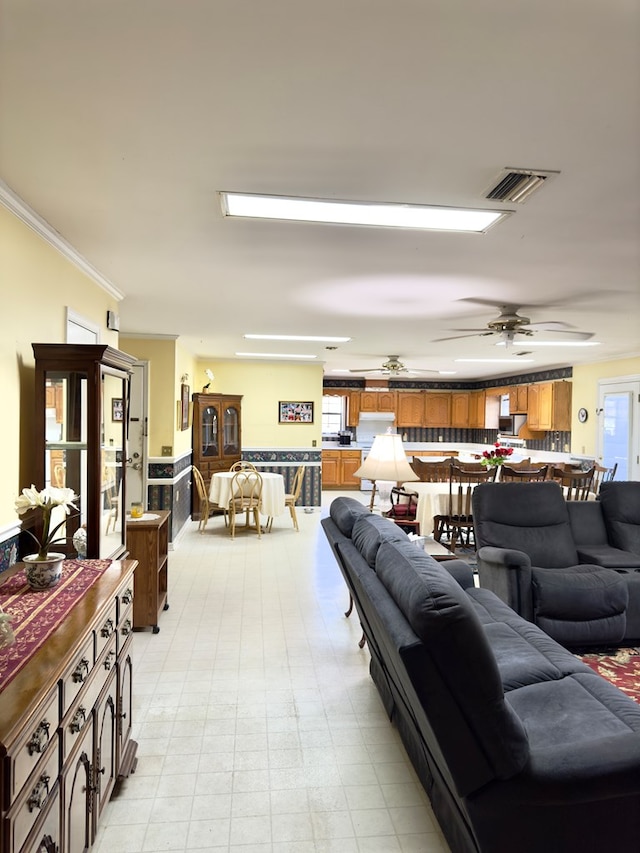 living room featuring ceiling fan, ornamental molding, visible vents, and a wealth of natural light