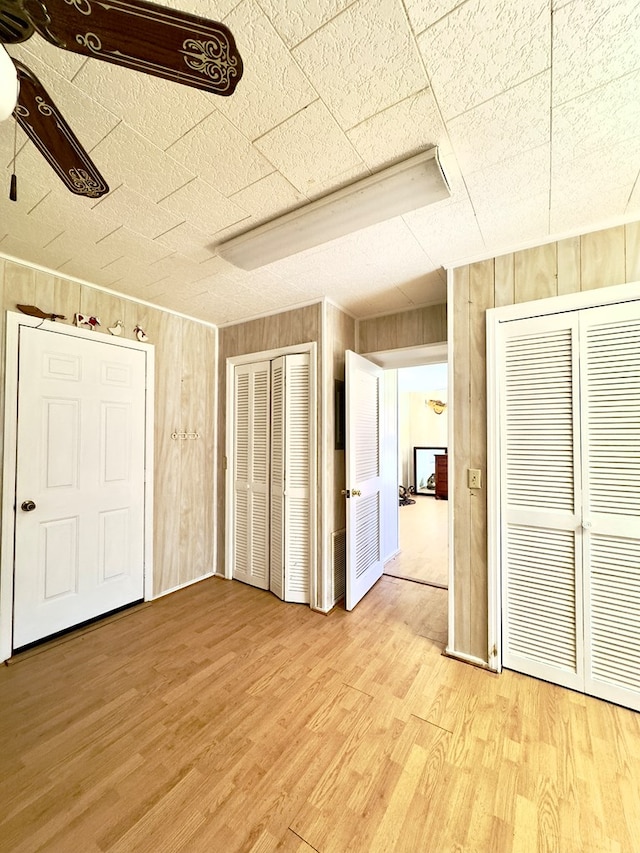 unfurnished bedroom featuring wood walls and light wood-style floors