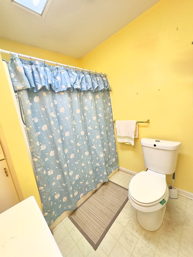 bathroom featuring curtained shower, baseboards, and toilet