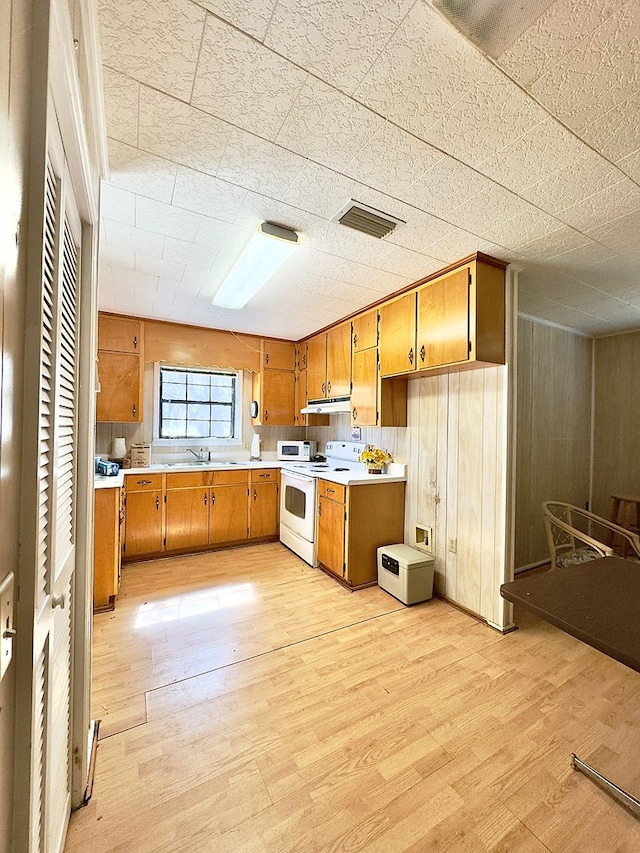 kitchen with visible vents, white range with electric cooktop, light countertops, light wood-style floors, and brown cabinets