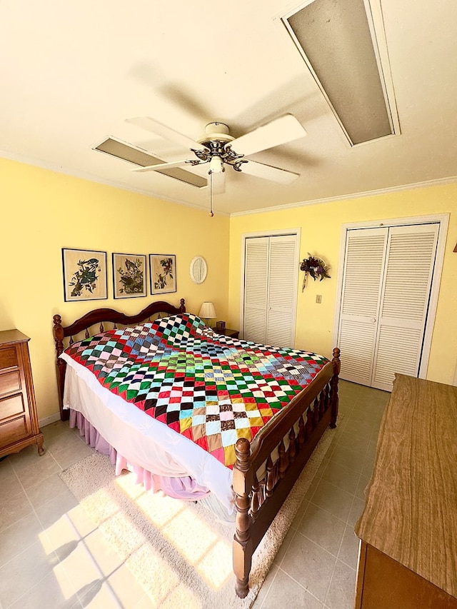 bedroom featuring multiple closets, attic access, a ceiling fan, and light tile patterned flooring