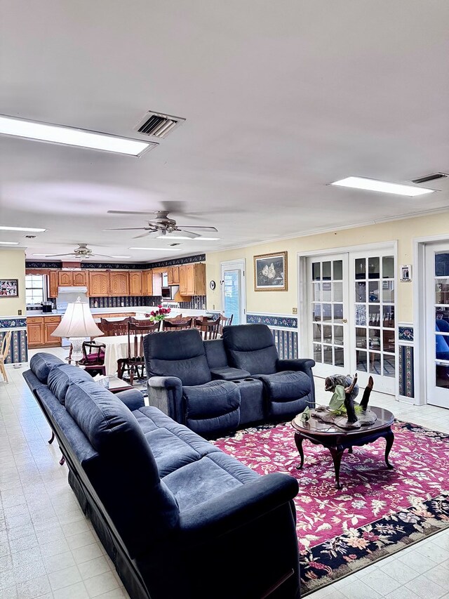 living room featuring a ceiling fan, visible vents, and a wealth of natural light