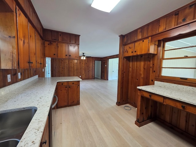 124 N Main St, Fitzgerald, GA 31750 - kitchen featuring light wood finished floors, stainless steel dishwasher, wooden walls, brown cabinets, and a peninsula