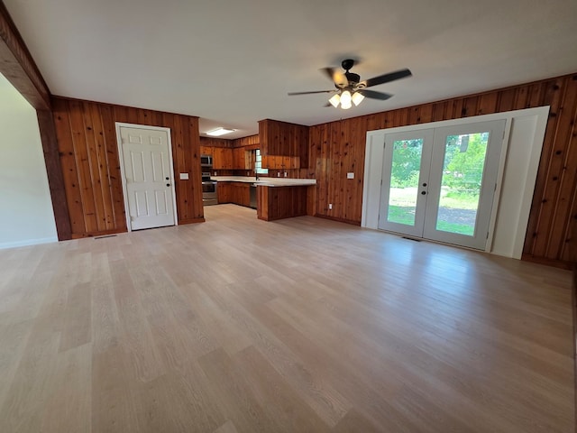 124 N Main St, Fitzgerald, GA 31750 - unfurnished living room with wooden walls, light wood-style flooring, ceiling fan, and french doors