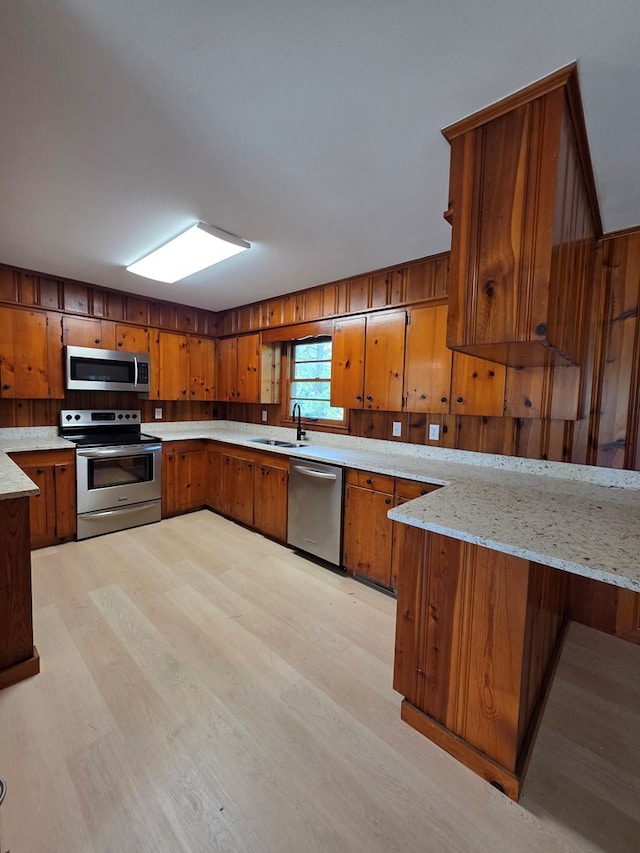 124 N Main St, Fitzgerald, GA 31750 - kitchen featuring stainless steel appliances, brown cabinetry, light wood-style floors, and wood walls