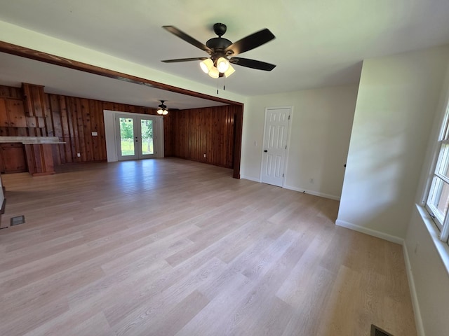 124 N Main St, Fitzgerald, GA 31750 - unfurnished living room with a ceiling fan, wood walls, light wood-style floors, and french doors