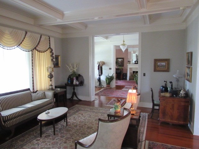living area with wood finished floors, beam ceiling, and coffered ceiling