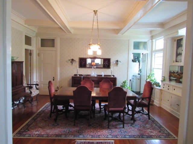 dining area with ornamental molding, wood finished floors, coffered ceiling, wallpapered walls, and beam ceiling