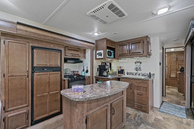 28 Bear Lovers Ct, Cleveland, GA 30528 - kitchen with stainless steel microwave, black range with gas cooktop, a center island, under cabinet range hood, and visible vents